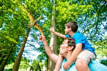 Father and son pointing to a model flying dinosaur in the trees