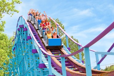 Families riding a blue and purple wooden roller coaster