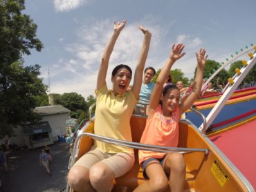 Woman and girl riding Twister ride with their hands in the air